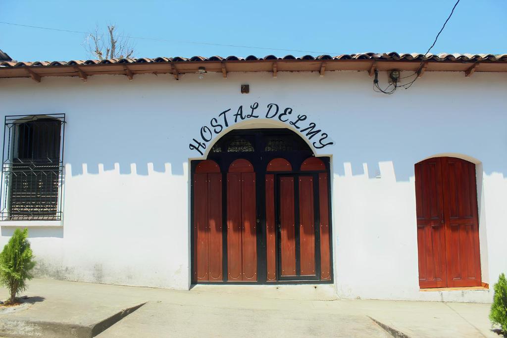 a white building with red doors and a sign on it at Hostal Delmy in Suchitoto