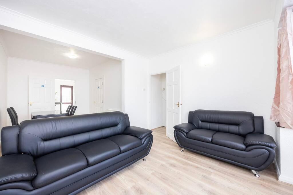 two black leather couches in a living room at 4 Bedroom House 2 baths Dagenham in Dagenham