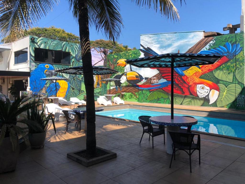 una piscina con mesas y sillas frente a un mural en Hotel Fenice, en Foz do Iguaçu