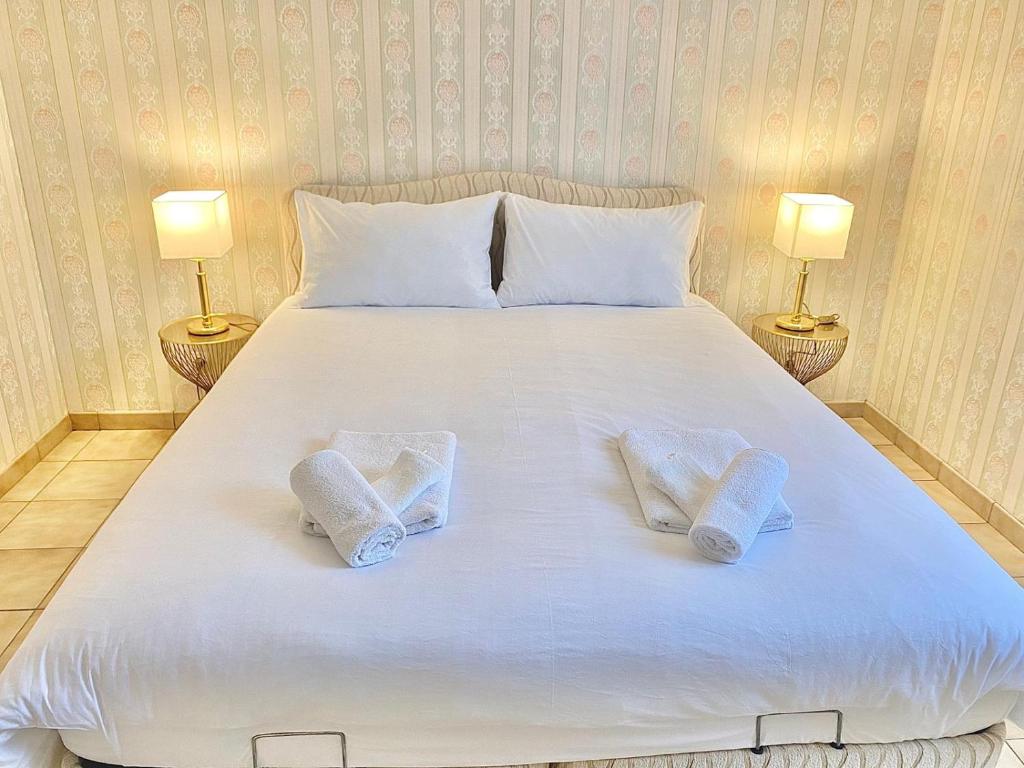 een groot wit bed met 2 handdoeken erop bij Villa Briconico in Gonesse