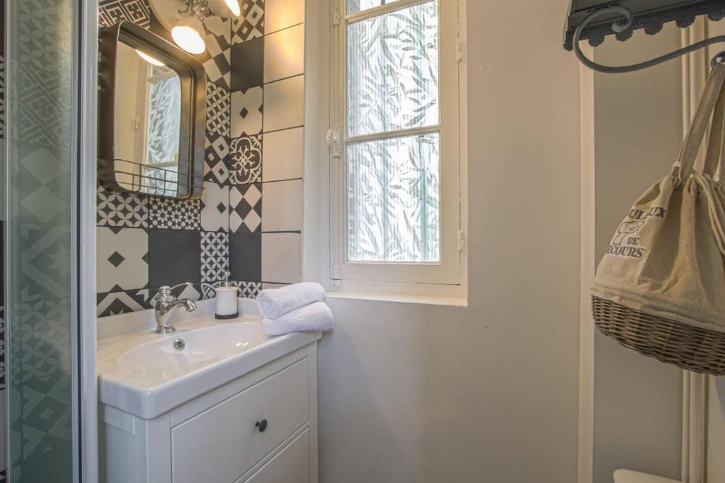 une salle de bain avec un lavabo et une fenêtre dans l'établissement Magnifique f2 en plein centre, à Cabourg