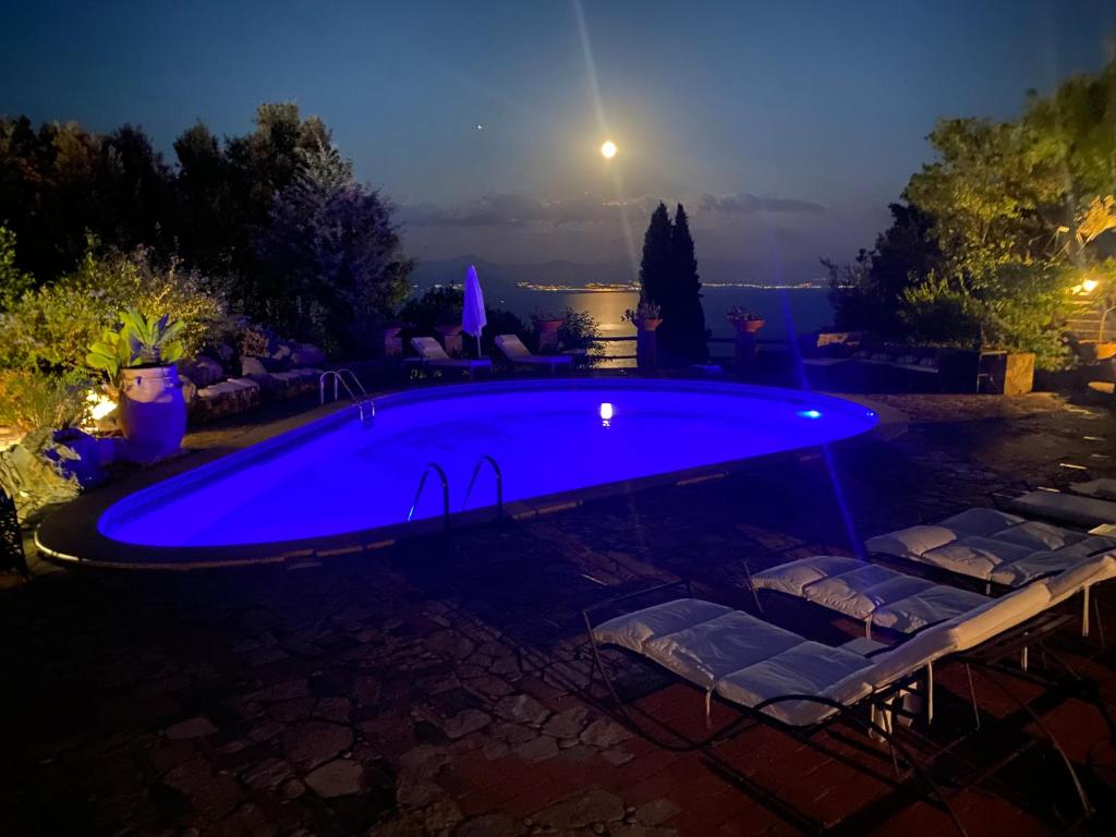 a large blue swimming pool in a backyard at night at Maison Du Reve Scario in Scario