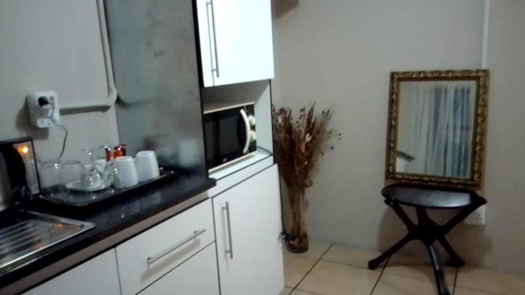 a kitchen with a counter and a mirror and a stool at Vee’s Guest House in East London