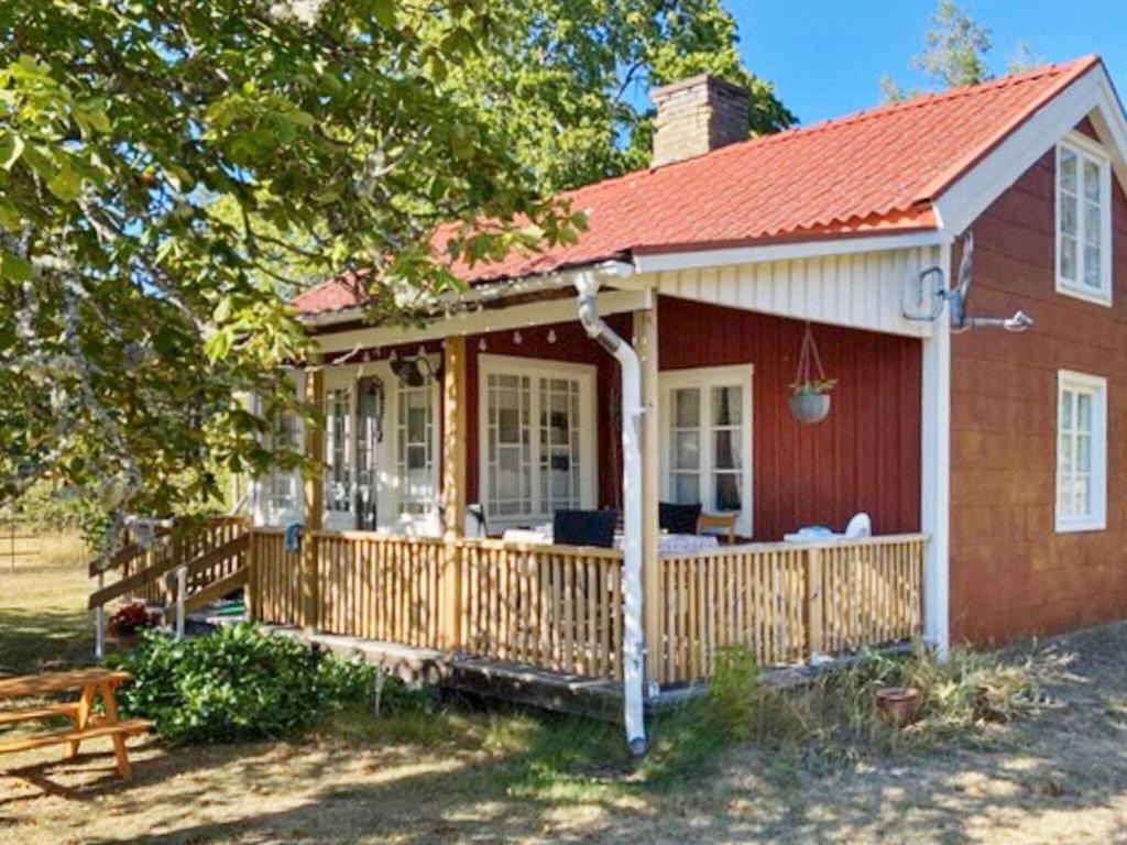 a small red house with a wooden deck at Idyllic Getaway with Private Beach in Abbetorp