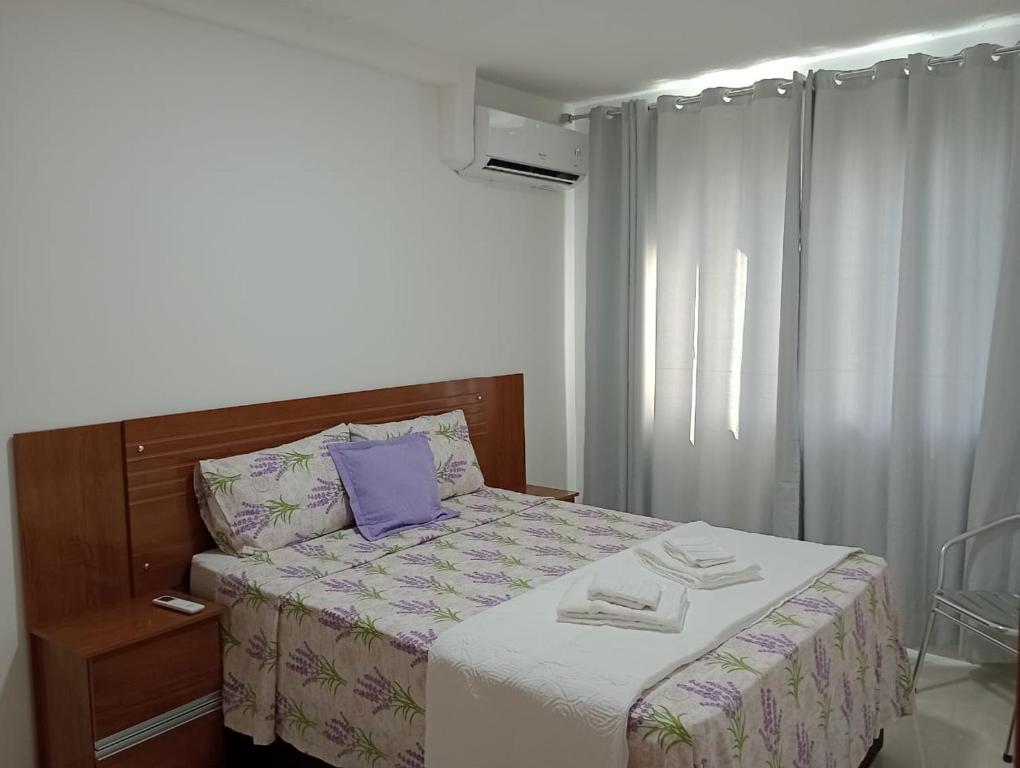 ein Schlafzimmer mit einem Bett mit einem lila Kissen in der Unterkunft La Palma 204 - Apartamento na Praia dos Milionários - Ilhéus/BA in Ilhéus