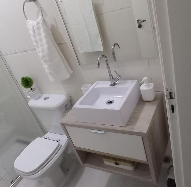 uma casa de banho branca com um lavatório e um WC em Ap 1 quarto Mobiliado em Gravataí