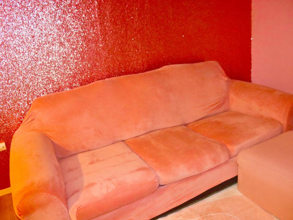 a brown leather couch sitting against a red wall at Think Pink in Fort Worth