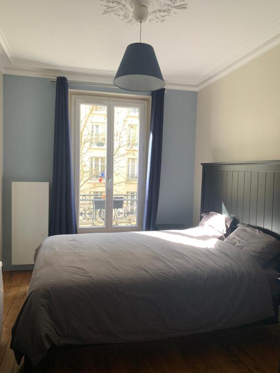 a bedroom with a bed and a large window at Chambre Quartier Auteuil in Paris