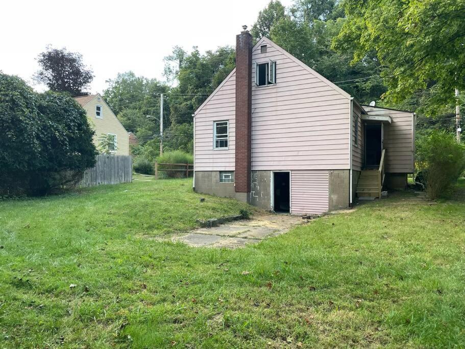 une vieille maison blanche dans un champ d'herbe dans l'établissement Cozy 4 bd house in Pitt, à Pittsburgh