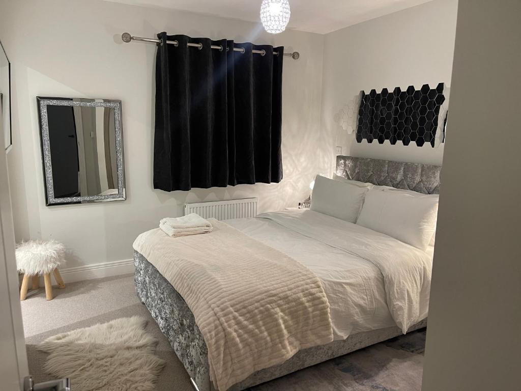Schlafzimmer mit einem großen Bett und schwarzen Vorhängen in der Unterkunft En-suite bedroom in a family home near Gatwick airport and Horley station in Hookwood