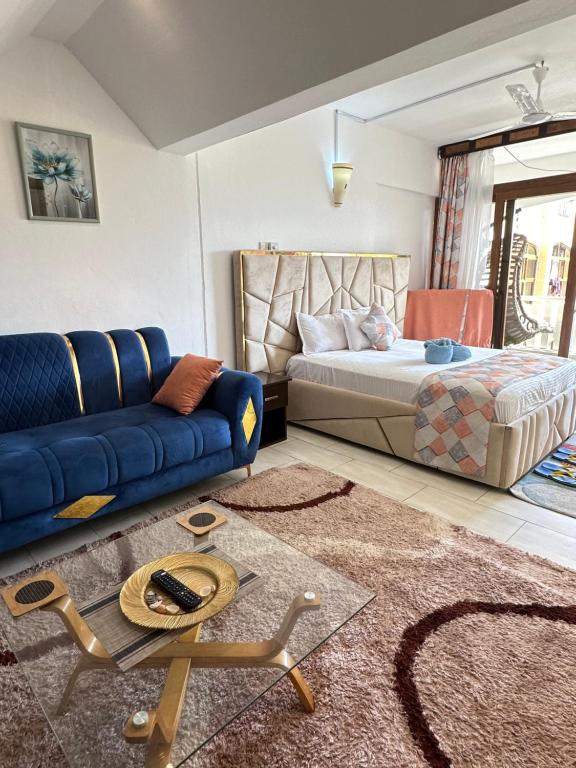 a living room with a bed and a blue couch at Sea la vie II in Kwale