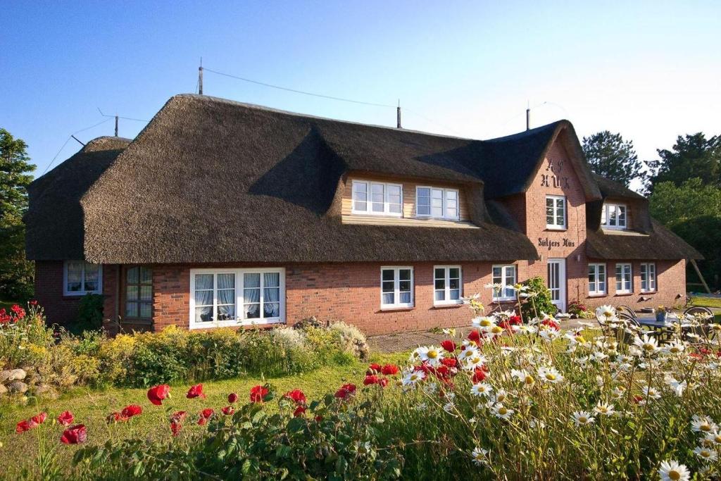 a house with a thatched roof and a field of flowers at Skuch-Looden in Süddorf