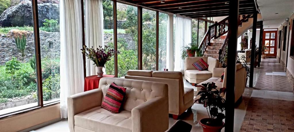 a living room with couches and large windows at Hotel Humantay Lodge Ollantaytambo in Ollantaytambo
