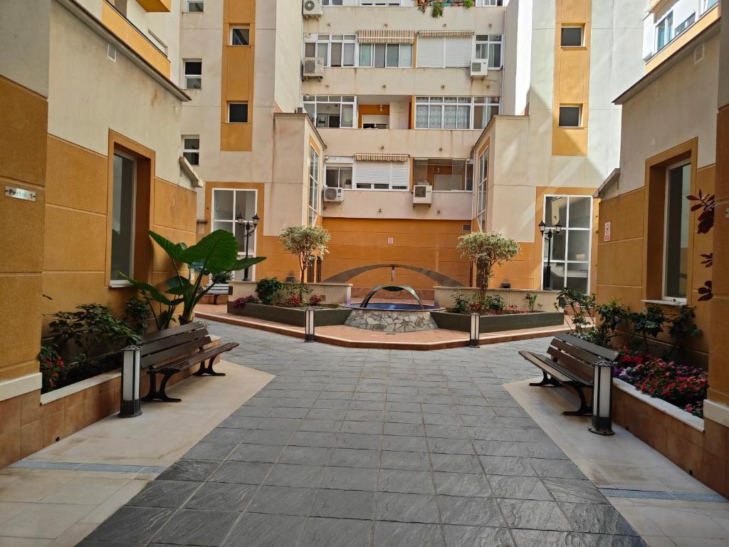 une cour d'un bâtiment avec des bancs et une fontaine dans l'établissement Suite Salitre12, à Malaga