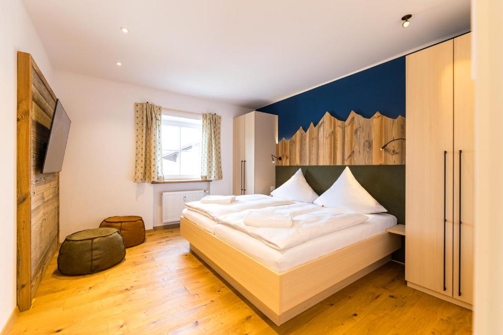 a bedroom with a large bed with a blue wall at LELA Apartments Chiemsee in Bernau am Chiemsee