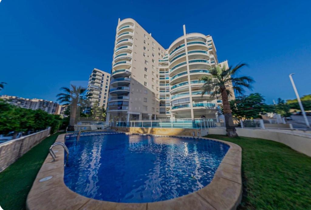 un edificio con piscina di fronte a un edificio di Bonito apartamento de la playa a Villajoyosa