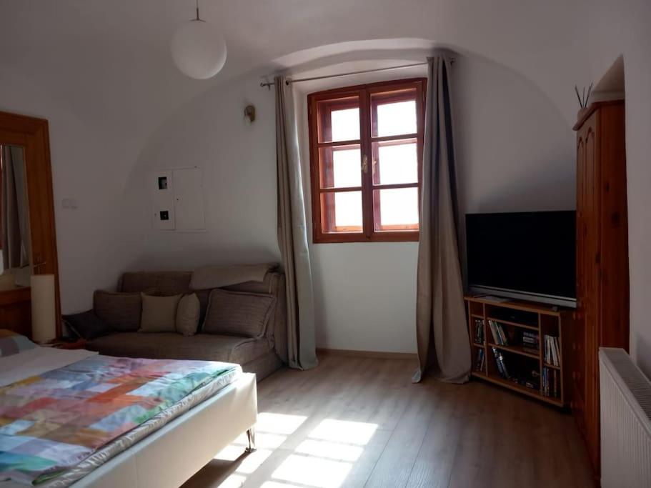 a bedroom with a bed and a couch and a window at Apartman Meda in Varaždin