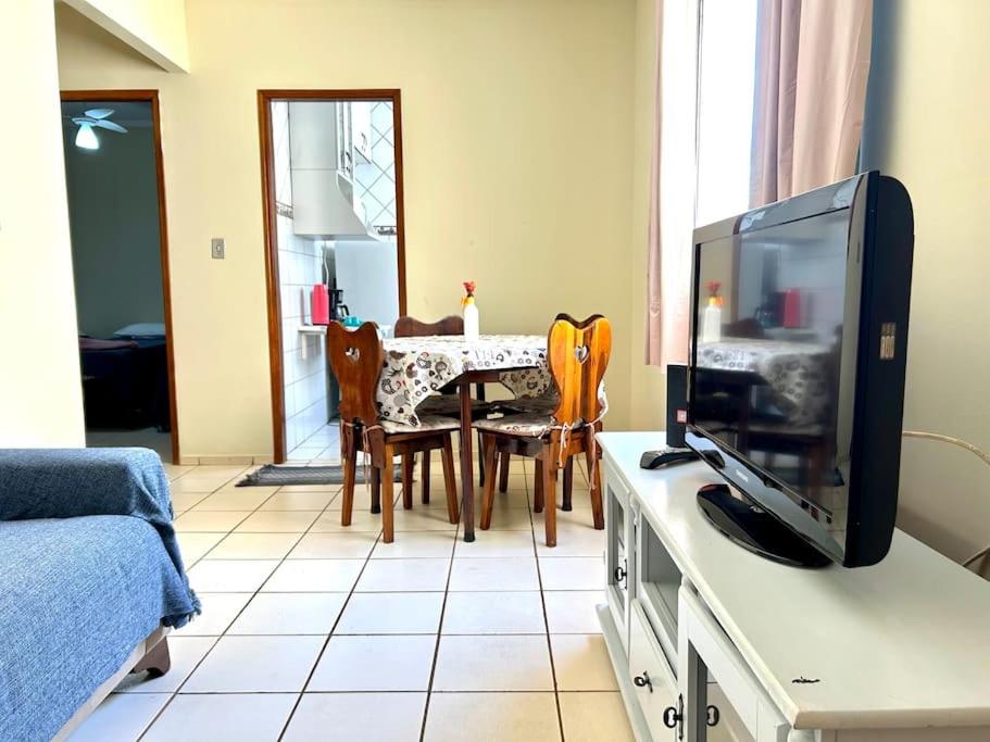 uma sala de estar com televisão e uma mesa com cadeiras em Apartamento Mobiliado em Piracicaba Centro em Piracicaba