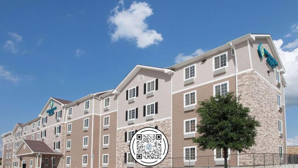 un gran edificio bronceado con un árbol delante de él en WoodSpring Suites College Station, en College Station
