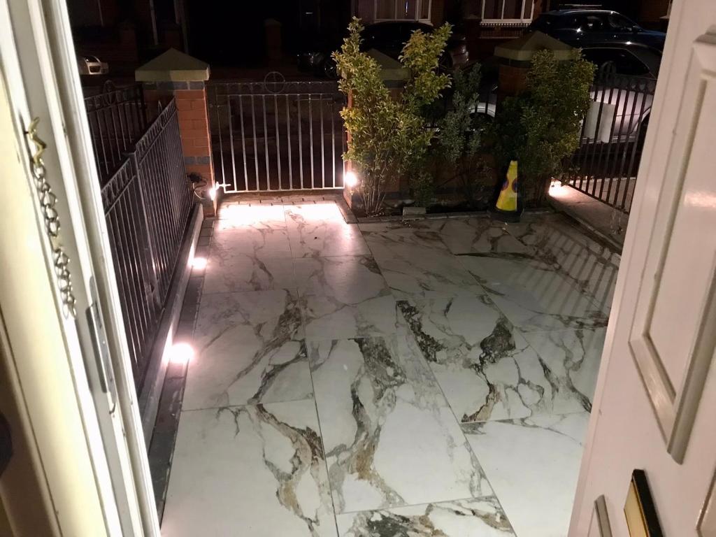 an outdoor patio with marble flooring at night with lights at Clayton Home in Manchester