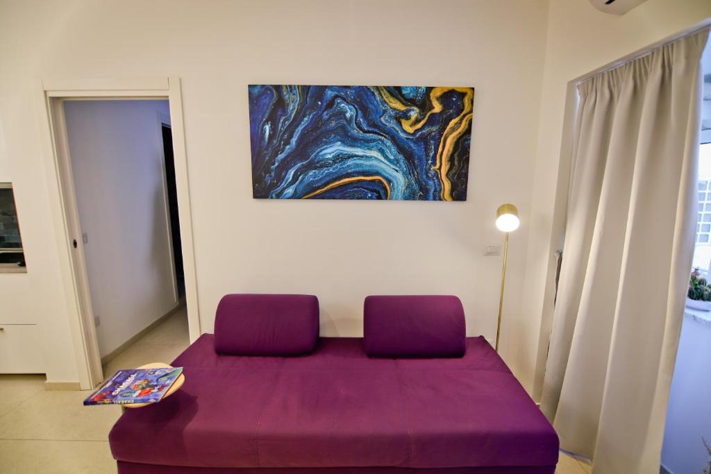 un divano viola in una stanza con un dipinto sul muro di Bovio 33 Napoli art apartment a Napoli