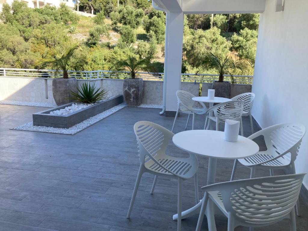 un patio avec des tables blanches, des chaises et des arbres dans l'établissement AleVa b&b, à Vieste