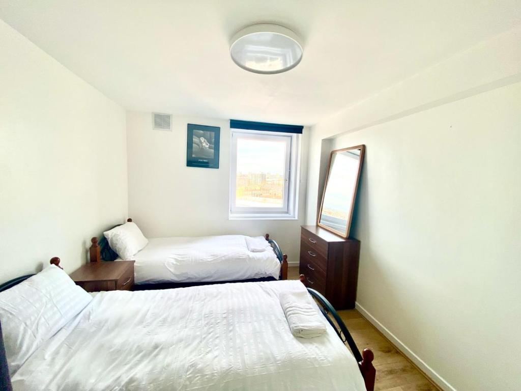 1 Schlafzimmer mit 2 Betten, einem Spiegel und einem Fenster in der Unterkunft Comfy Two bedroom Flat Edgeware Road In Central London in London