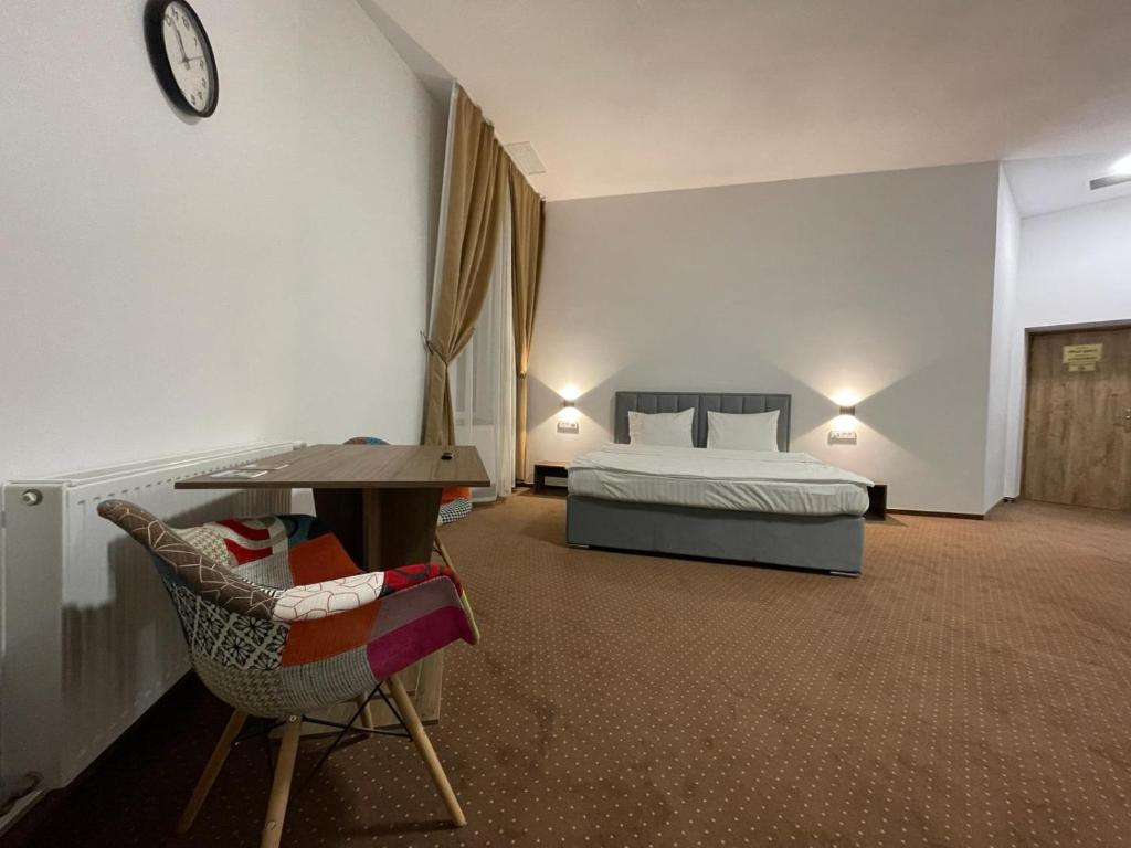 a bedroom with a bed and a desk and a chair at Resedinta Cina in Braşov