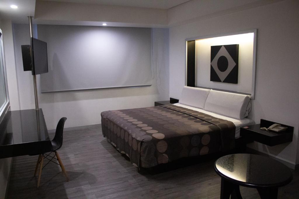 A compact single-bed room with a wall-mounted TV, desk and small round table.