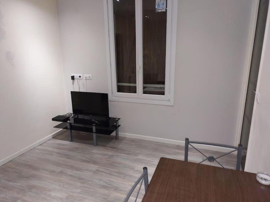 Una sala de estar con una mesa y un televisor en una habitación. en Le Shelby's - Appartement cosy et lumineux !, en Villeneuve-Saint-Georges