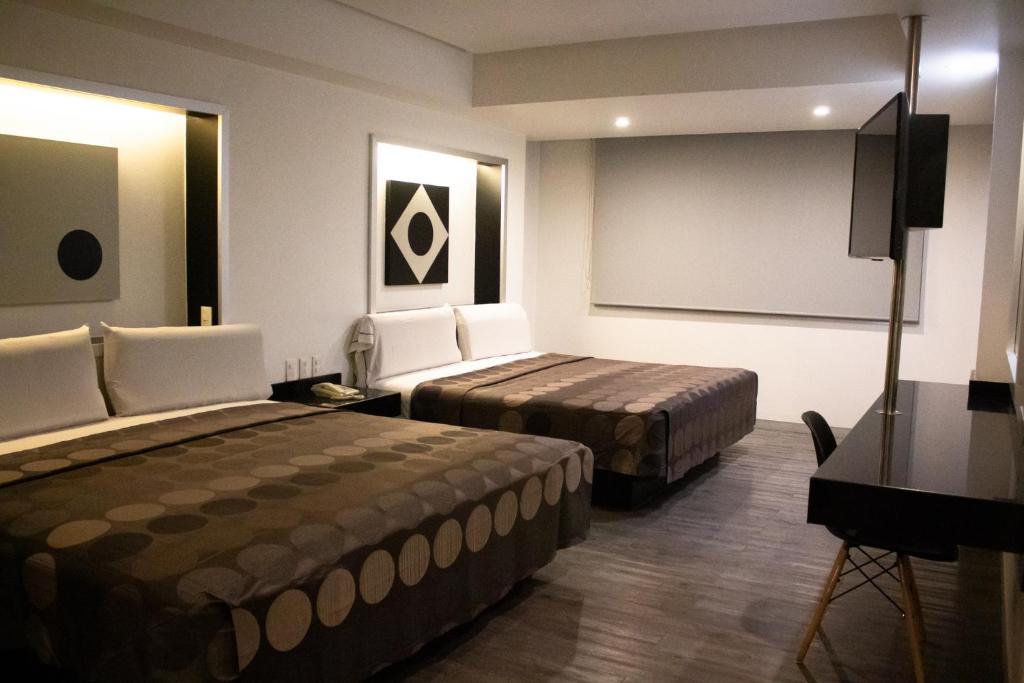 A twin room with two beds, a wall-mounted television and a compact workspace.