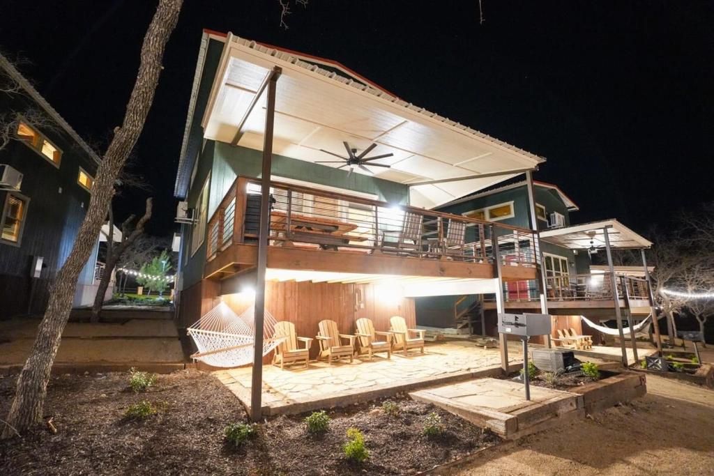 una casa con una terraza con sillas por la noche en Spacious Modern Lux Cabin Hot Tub FirePit Games, en Runaway Bay