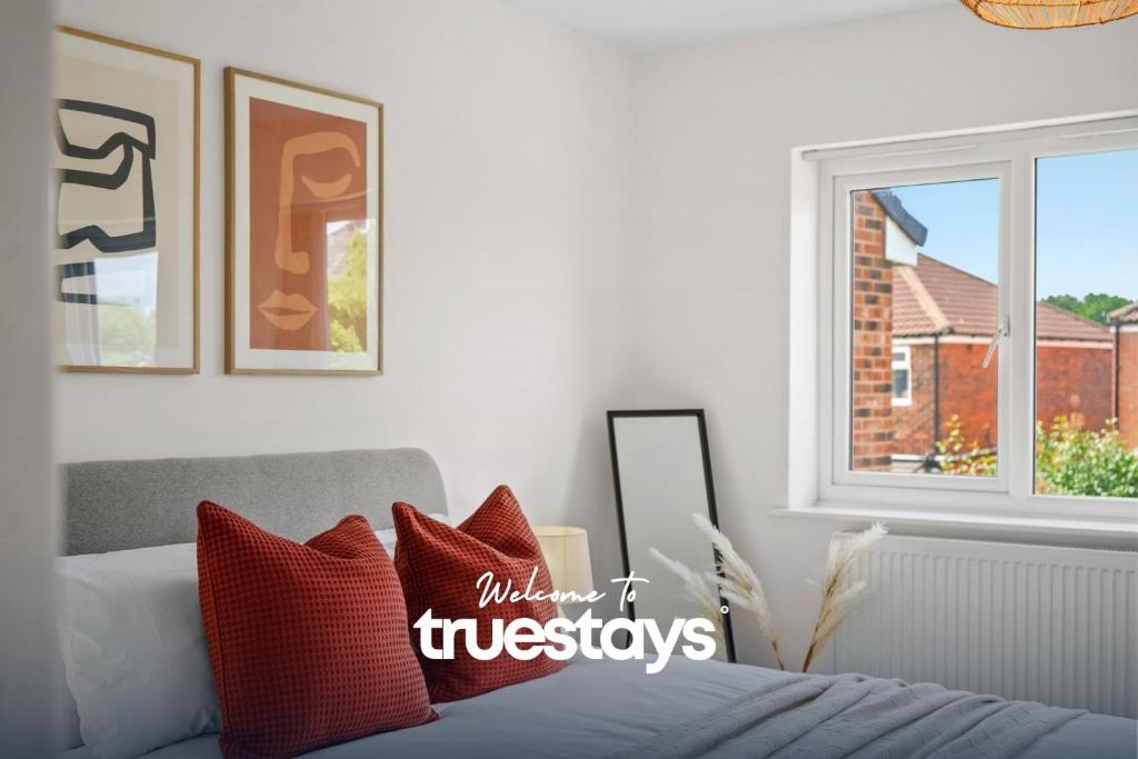 um quarto com uma cama com almofadas vermelhas e uma janela em Greaves House by Truestays - 3 Bedroom House in Failsworth, Manchester em Manchester