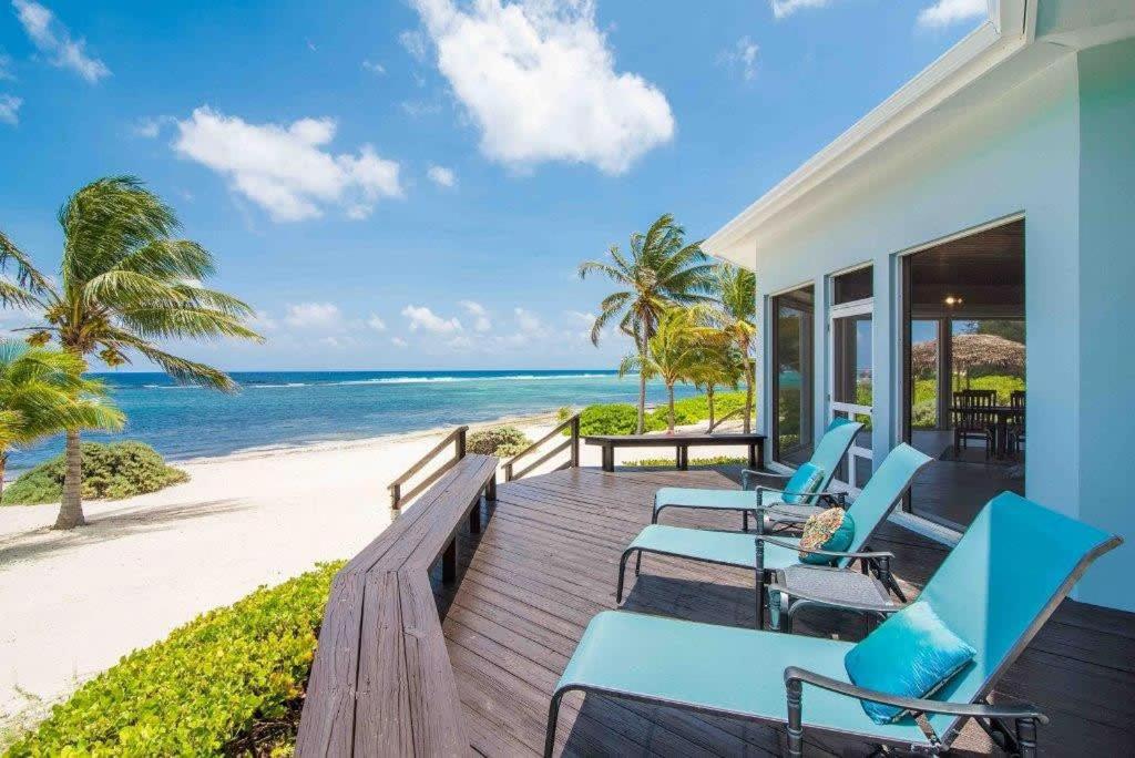 una veranda con sedie blu e la spiaggia di Peaceful Ocean Front Beach House in Bodden Town a Bodden Town