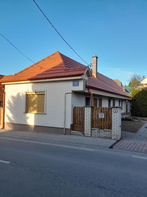 una casa blanca con techo rojo en una calle en Falusi Vendégház, en Etyek