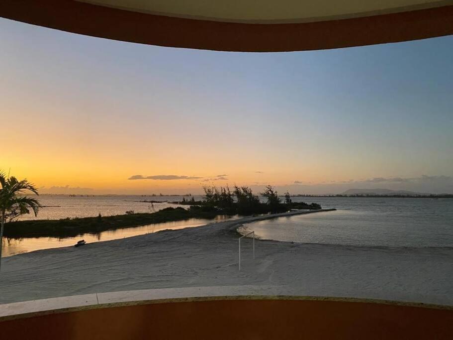 - une vue sur la plage au coucher du soleil et l'océan dans l'établissement Apartamento Arraial do Cabo, à Arraial do Cabo