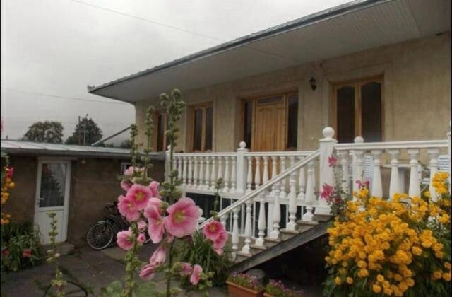a house with a porch with flowers in front of it at Nino's Guest House in Stepantsminda