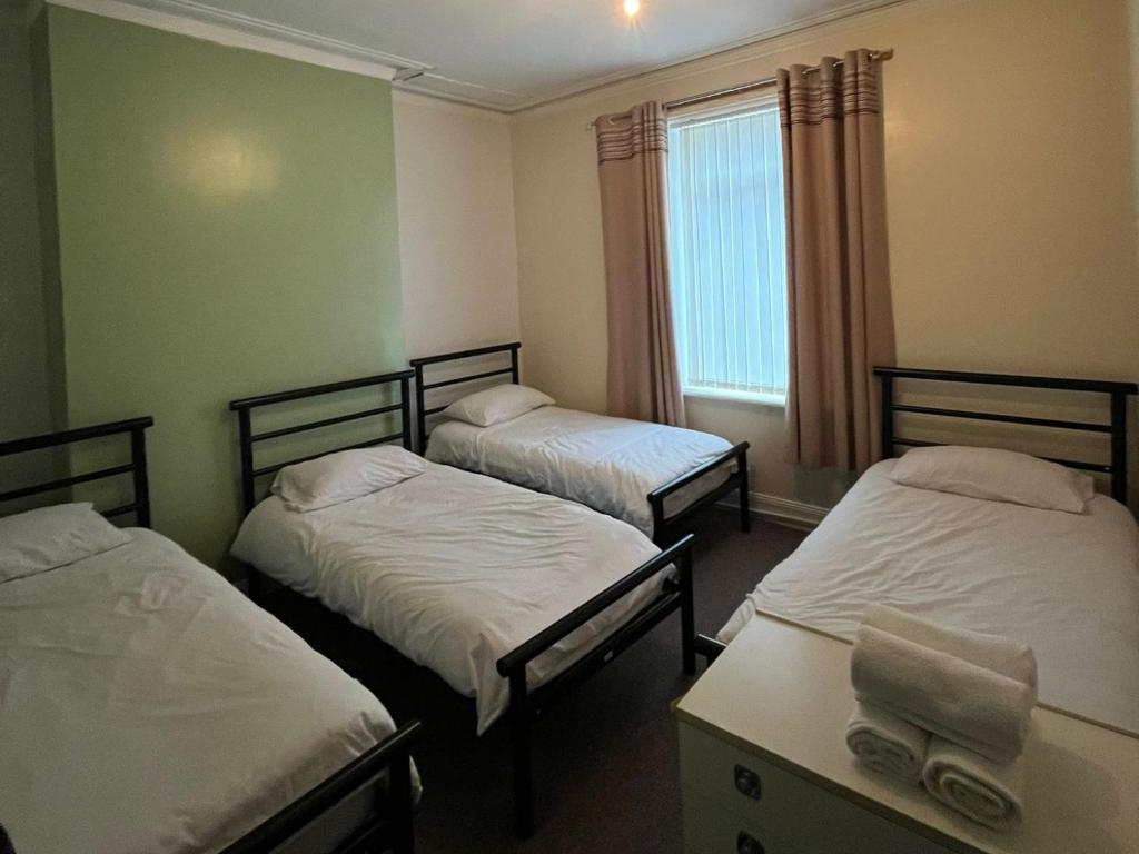 a room with three beds and a window at Arthurs Hill Newcastle, free parking fully equipped kitchen 4 bedrooms, Near city centre in Newcastle upon Tyne