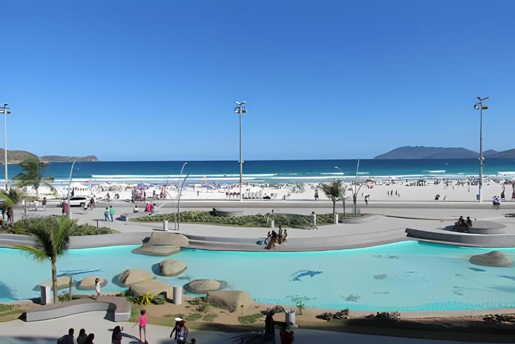 uma vista para a praia e uma piscina num resort em PRAIA DO FORTE ALTO LUXO em Cabo Frio