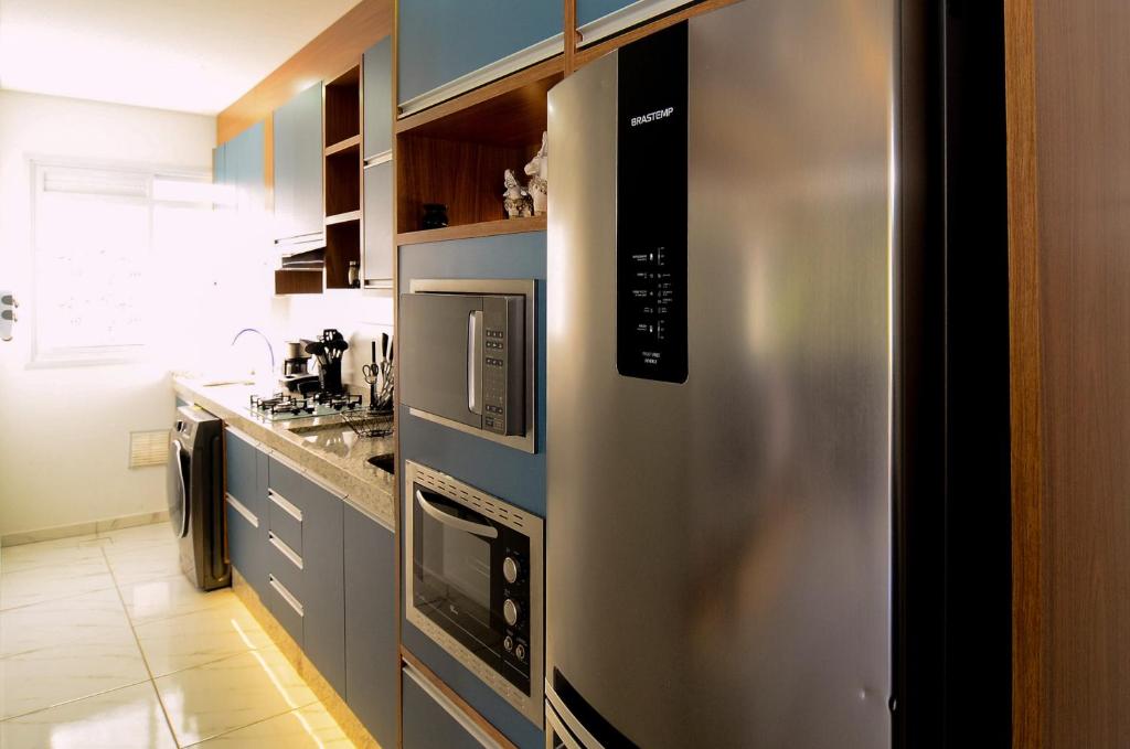 uma cozinha com um frigorífico de aço inoxidável e um micro-ondas em Apt luxo na área nobre Ingleses em Florianópolis