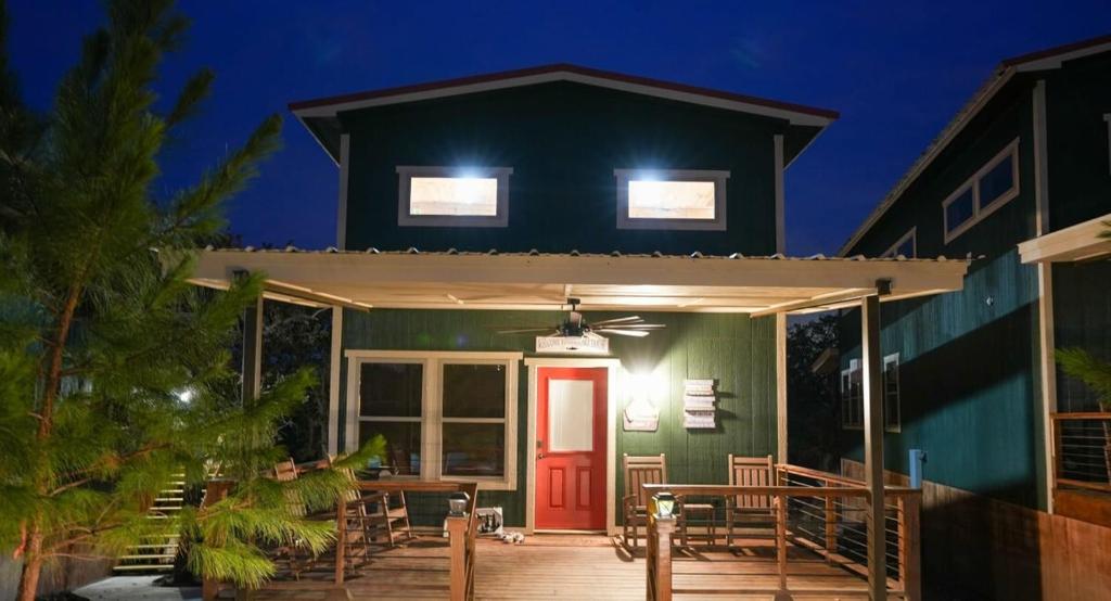 una casa verde con una puerta roja por la noche en CampQYB- Modern Lux Cabin Hot Tub FirePit Sauna, 