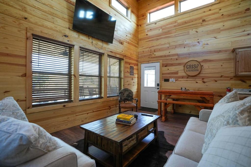 a living room with a couch and a table in a cabin at CampQYB- Modern Lux Cabin Hot Tub FirePit Sauna in Runaway Bay