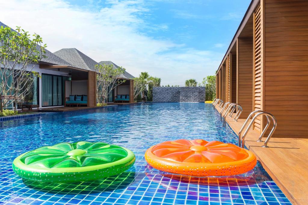 uma piscina com dois insufláveis coloridos em Vann Hua Hin Resort em Cha Am