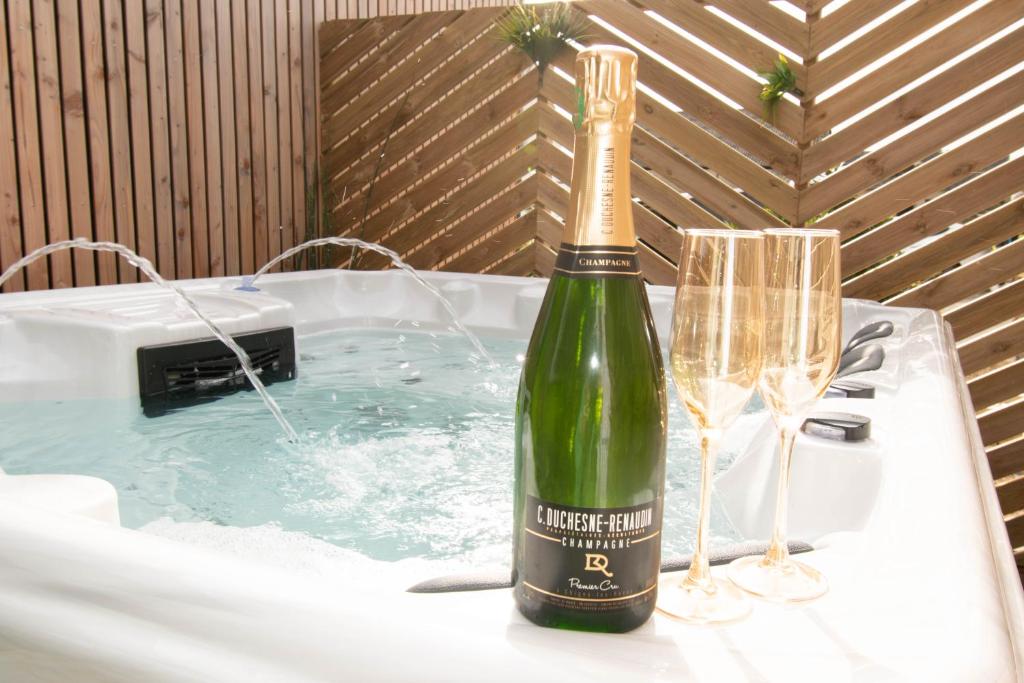 a bottle of champagne sitting on a table in a bath tub at Studio les 2 fées - Brocéliande - Jacuzzi couvert in Montfort-sur-Meu