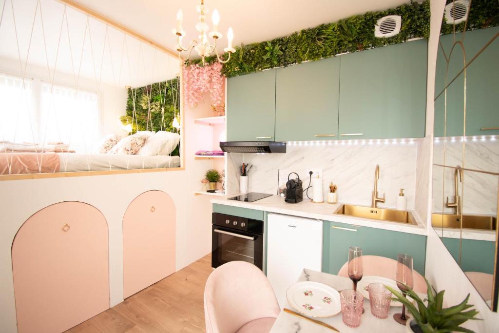 uma cozinha com armários verdes e uma mesa e cadeiras em Studio les 2 fées - Jacuzzi et Décoration Enchantée em Montfort-sur-Meu