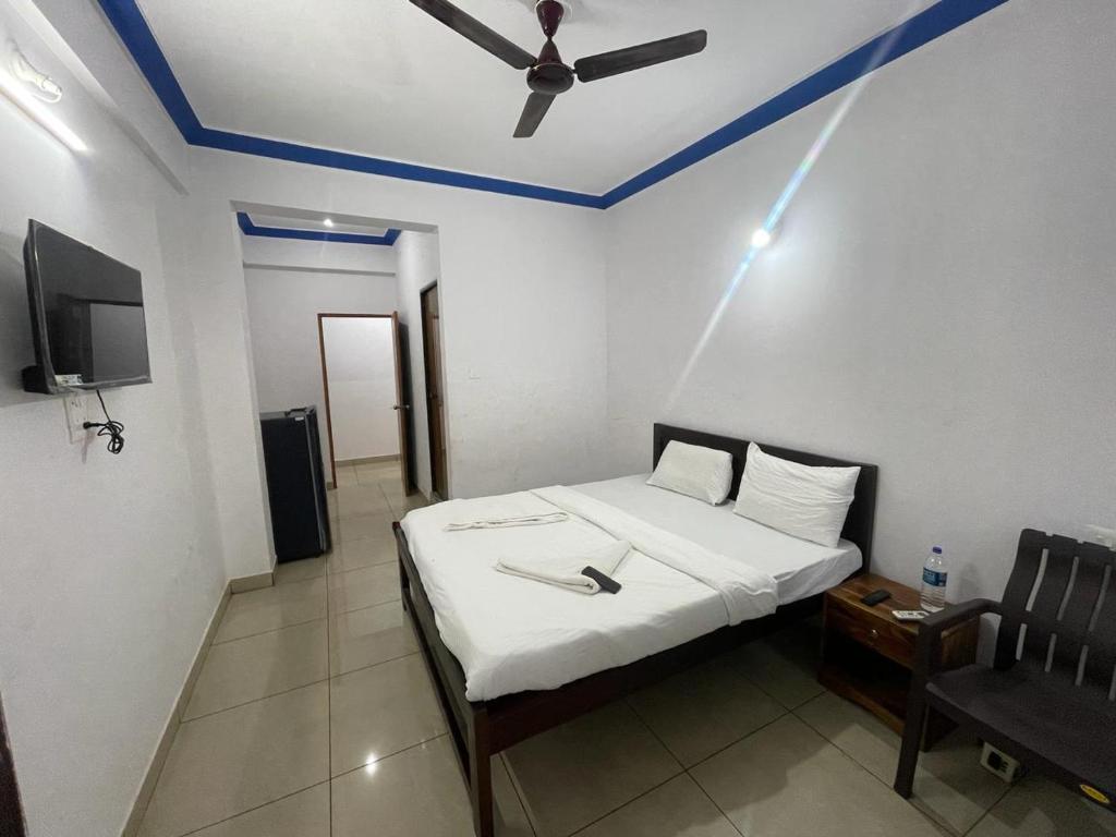a bedroom with a bed with a ceiling fan and a chair at Hotel Lake View Baga in Arpora