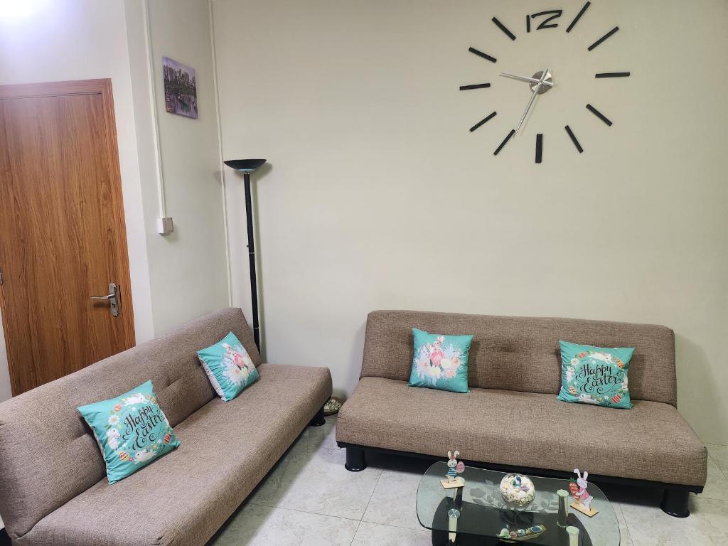 a living room with two couches and a clock on the wall at Kot Nu - Beach Themed Apartment - 3 mins walk from the sea in Flic-en-Flac