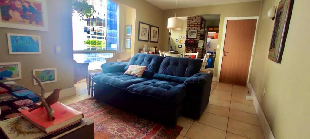 uma sala de estar com um sofá azul e uma janela em Apartamento com localização fantástica na praia de Balneário Camboriú em Balneário Camboriú