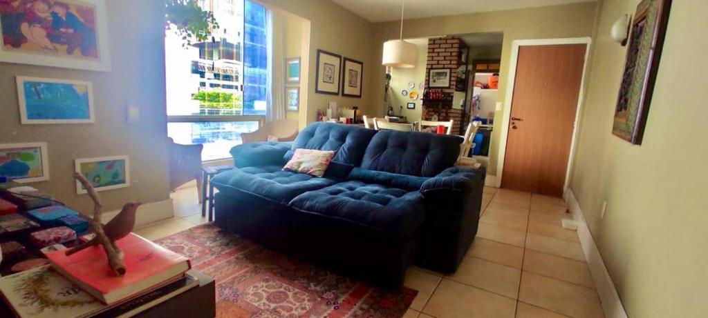 a living room with a blue couch and a window at Apartamento com localização fantástica na praia de Balneário Camboriú in Balneário Camboriú