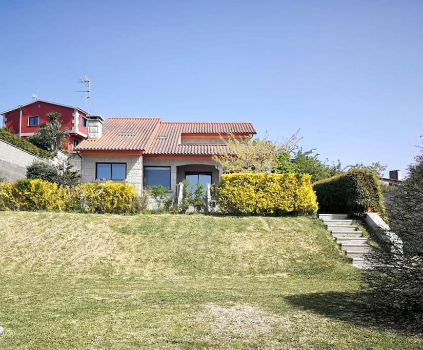 ein Haus auf einem Hügel mit einem Rasenplatz in der Unterkunft Villa Charneca, jardín y mar in Vigo